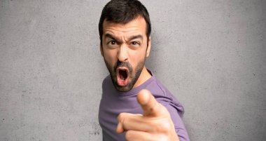 Yakışıklı adam kötü bir durum tarafından sinirli ve dokulu duvar üzerinde ön işaret