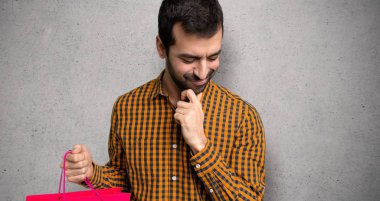 Dokulu duvarın üzerinde çene üzerinde el ile aşağı bakan alışveriş çantaları ile Adam