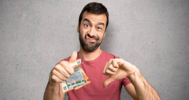 İyi-kötü işareti yaparak çok para alan bir adam. Evet ya da dokulu duvar üzerinde kararsız