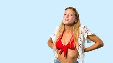 Yaz tatilinde sarışın kız mavi arka plan üzerinde bir çaba yapmış olduğu için sırt ağrısı muzdarip