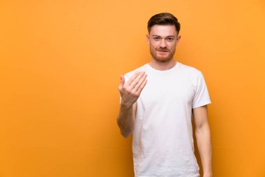 Kahverengi duvarın üzerinde kızıl saçlı adam el ele gelmeye davet ediyor. Geldiğin için mutluyum.