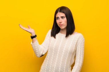 İzole edilmiş sarı duvarın üzerindeki genç kadın kopyalama alanını kuşkularla dolduruyor