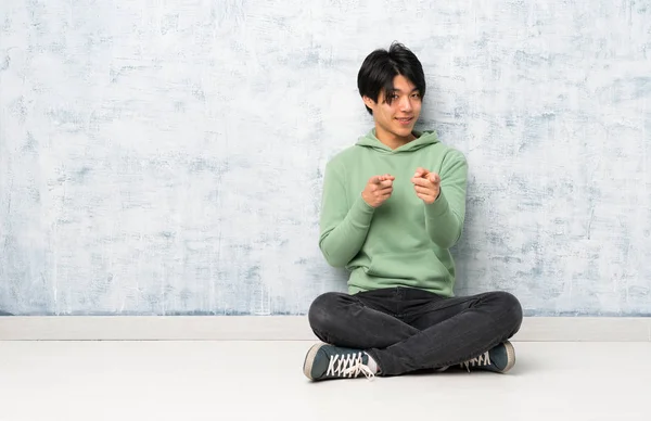Asiatischer Mann Sitzt Auf Dem Boden Und Zeigt Nach Vorne — Stockfoto