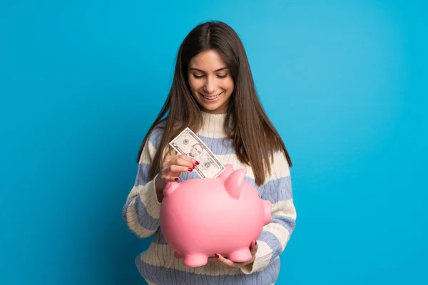 Jovem Mulher Sobre Parede Azul Tomando Banco Porquinho Feliz Porque — Fotografia de Stock