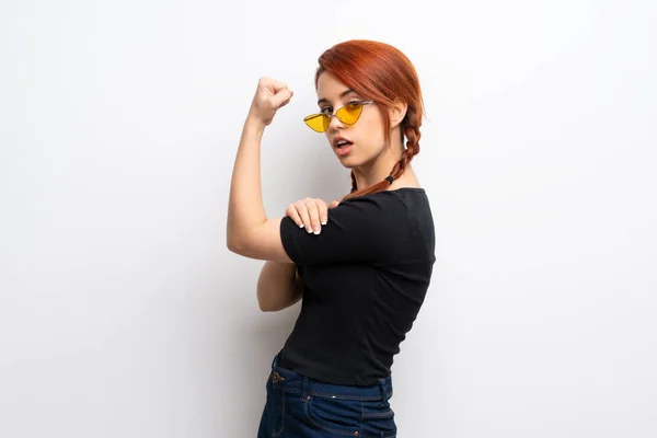 Young redhead woman over white wall Doing strong gesture