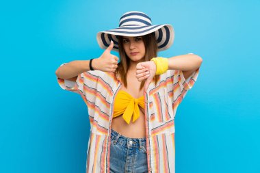 Yaz tatilinde bikinili genç bir kadın iyiye kötüye işaret yapıyor. Evet ya da hayır arasında kararsız