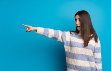 Mavi duvarın üzerinde genç kadın işaret