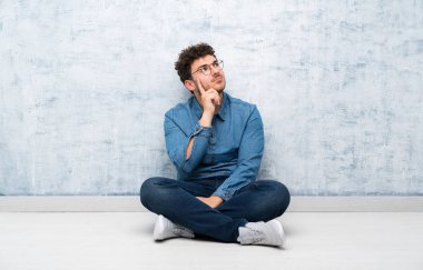 Gözlükle yerde oturan genç adam