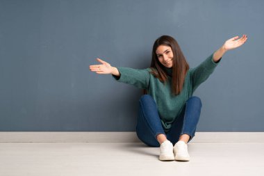 Genç bayan yerde oturuyor, sunuyor ve davet ediyor.