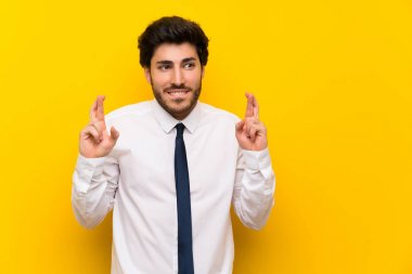 Parmakları geçerken izole sarı arka plan üzerinde işadamı
