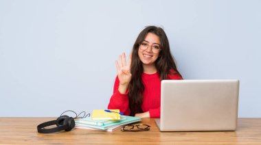Genç öğrenci kız mutlu bir masada okuyan ve parmakları ile dört sayma