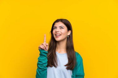 Genç kız harika bir fikir işaret parmağı ile işaret sarı duvarın üzerinden