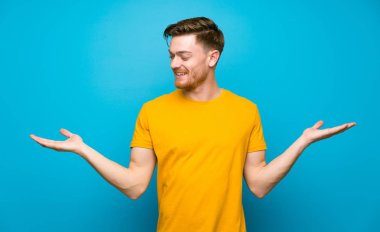 İki eliyle copyspace tutan mavi duvar üzerinde Redhead adam