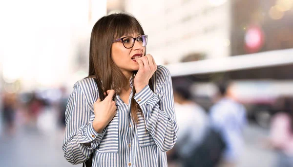 Woman with glasses nervous and scared putting hands to mouth at outdoors