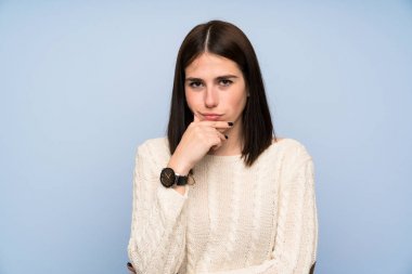 Izole mavi duvar ayakta ve bir fikir düşünme üzerinde genç kadın