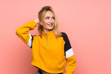 Soyutlanmış pembe arka planı olan genç sarışın kadın bir fikir düşünüyor.