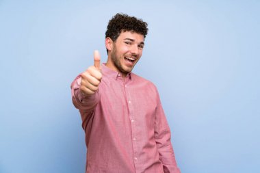 İyi bir şey oldu çünkü başparmak ile izole mavi duvar üzerinde kıvırcık saçlı adam