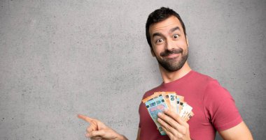 Adam dokulu duvar üzerinde yanal pozisyonda yan parmak işaret eden para çok alarak