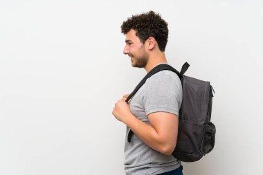 Sırt çantası ile izole duvar üzerinde kıvırcık saçlı Adam