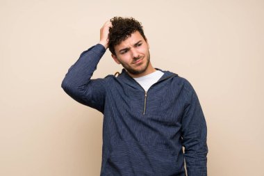 Başını çizerken şüpheleri olan izole duvar üzerinde kıvırcık saçlı adam