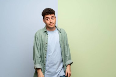 Mavi ve yeşil geçmişi olan genç bir adam önemsiz bir jest yapıyor.