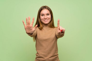 Balıkçı yaka kazaklı genç kadın parmaklarıyla altıyı sayıyor.