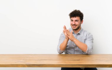 Bir konferansta sunumdan sonra masadaki genç adam alkışlıyor.