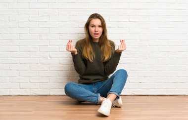 Genç bir kadın yerde oturmuş para hareketi yapıyor.