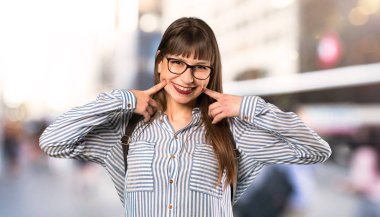 Açık havada mutlu ve hoş bir ifade ile gülümseyen gözlük kadın