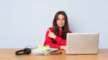 Bir ürün sunmak için yan işaret eden bir tabloda okuyan genç öğrenci kız