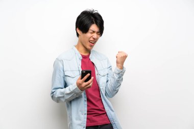 Zafer pozisyonunda telefon ile izole beyaz arka plan asyalı adam