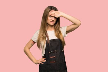 Young woman with apron with tired and sick expression on isolated pink background
