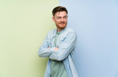 Kolları çapraz ve mutlu ile renkli arka plan üzerinde Redhead adam