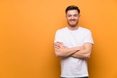 Kollarını ön pozisyonda çapraz tutan kahverengi duvar üzerinde Redhead adam