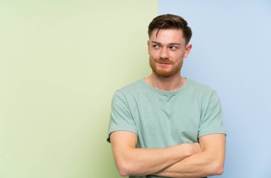 Renkli arka plan ayakta üzerinde Redhead adam ve yan bakıyor