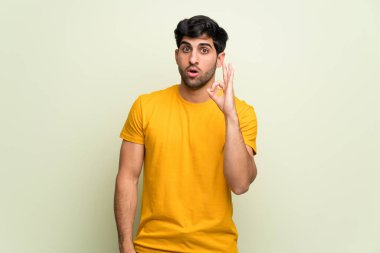 Pembe duvarın üzerindeki genç adam şaşırdı ve tamam işareti gösteriyor.