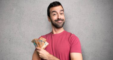 Dokulu duvarın üzerinde ön pozisyonda kollarını çapraz tutarak çok para alan adam