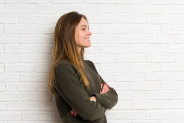 Beyaz tuğla duvar ayakta ve yan bakıyor genç kadın