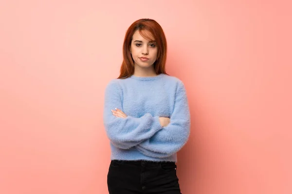 Young redhead woman over pink background angry