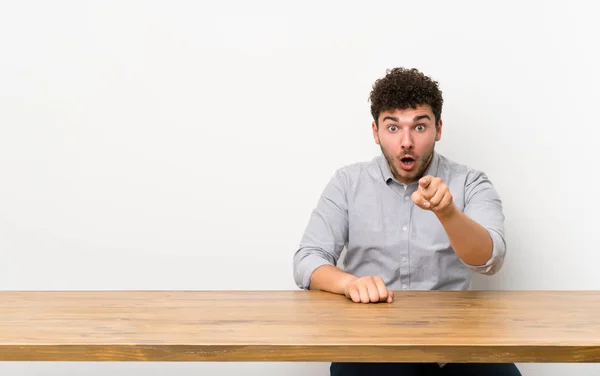 Jeune Homme Avec Une Table Surpris Pointant Vers Avant — Photo