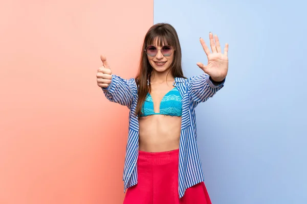 Young woman in bikini counting six with fingers