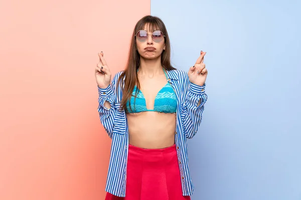 Young woman in bikini with fingers crossing and wishing the best