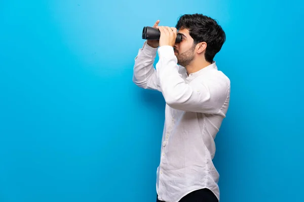 Jonge Man Geïsoleerde Blauwe Muur Kijken Verte Met Verrekijker — Stockfoto