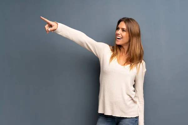 Mujer Rubia Sobre Fondo Gris Apuntando Lejos —  Fotos de Stock