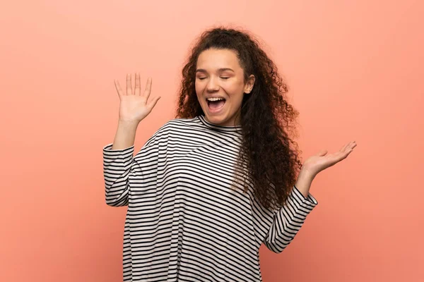 Teenager girl over pink wall smiling a lot