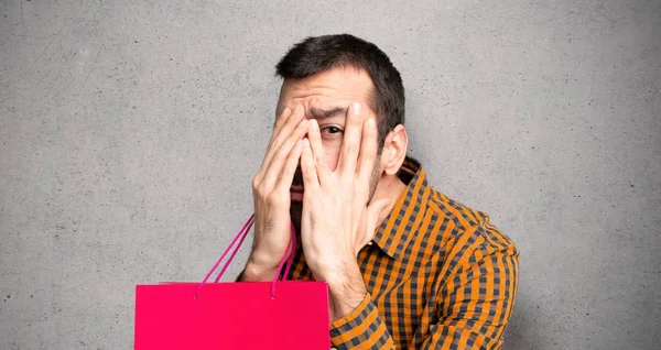 Man Shopping Bags Covering Eyes Hands Looking Fingers Textured Wall — Stock Photo, Image