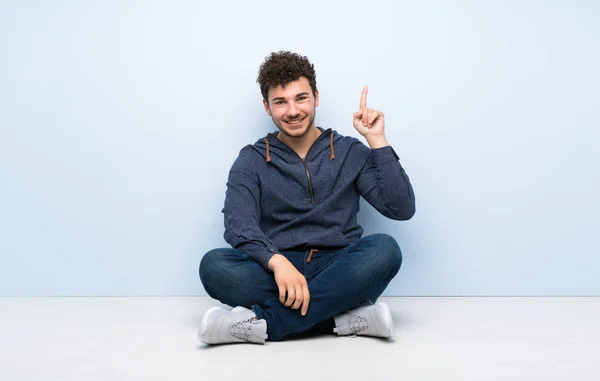 Junger Mann Sitzt Auf Dem Boden Und Zeigt Und Hebt — Stockfoto