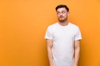 Kahverengi duvar üzerinde Redhead adam yan görünümlü şüphe jest yapma