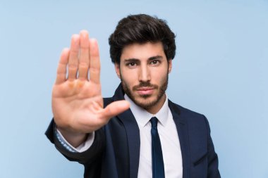 İzole mavi duvar üzerinde işadamı stop jest yapma