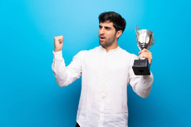 Bir kupa tutan izole mavi duvar üzerinde genç adam